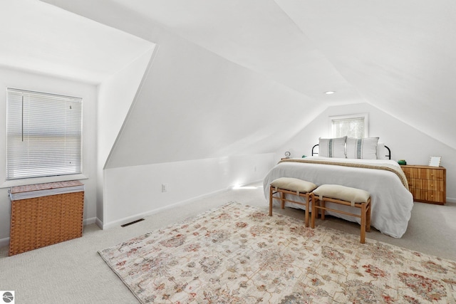 carpeted bedroom featuring lofted ceiling, baseboards, and visible vents