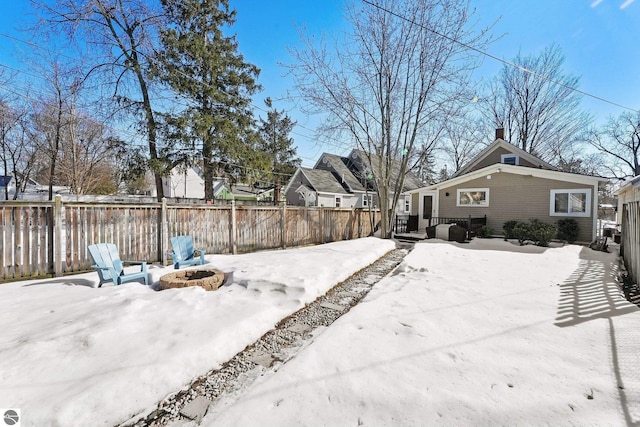 snowy yard featuring a fire pit and fence