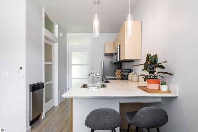 kitchen featuring a peninsula, stove, a sink, light countertops, and stainless steel microwave