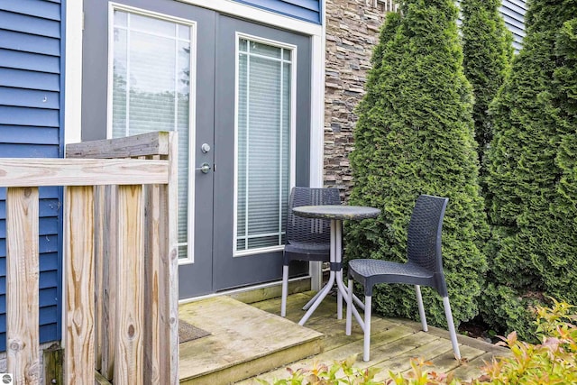 view of exterior entry with stone siding and a deck