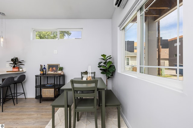 dining room featuring a wall unit AC, baseboards, and wood finished floors