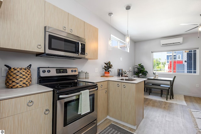 kitchen featuring appliances with stainless steel finishes, a peninsula, light countertops, an AC wall unit, and light brown cabinetry