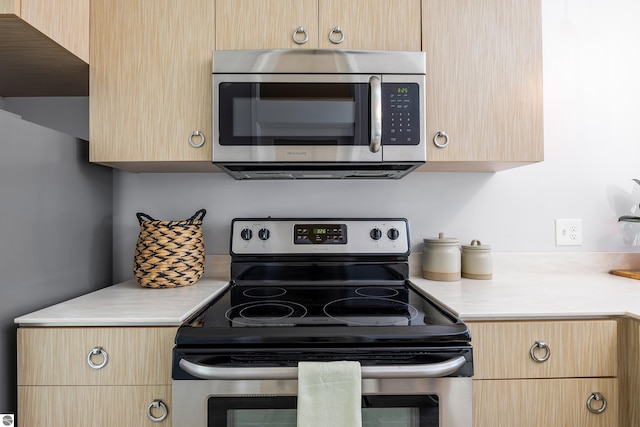 kitchen with stainless steel appliances, light brown cabinets, and light countertops