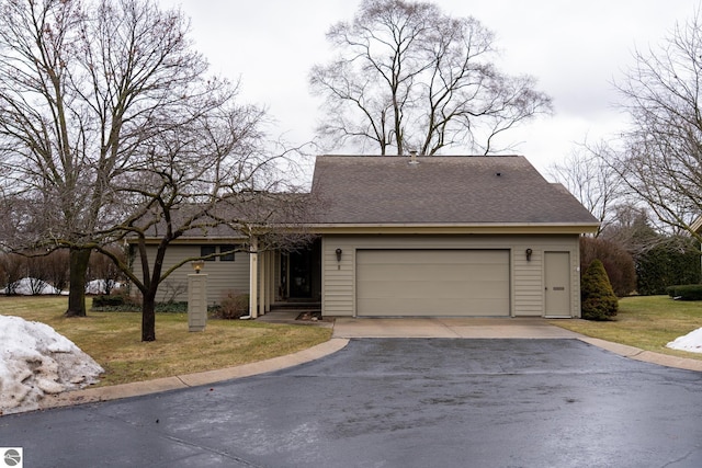 view of front of property with aphalt driveway, a front yard, a shingled roof, and a garage