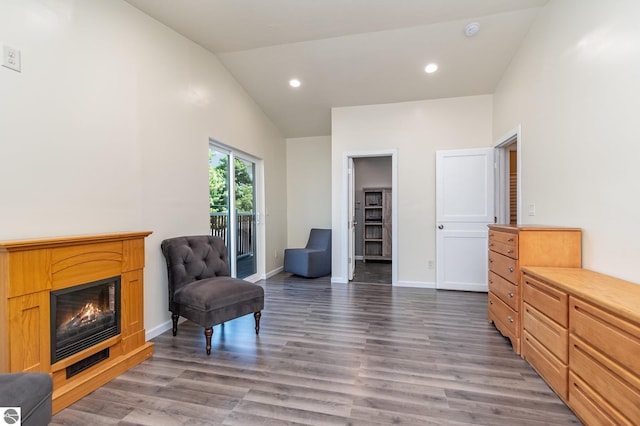 living area featuring lofted ceiling, wood finished floors, a glass covered fireplace, and recessed lighting