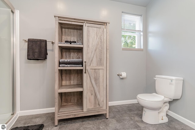 bathroom with a shower with shower door, toilet, and baseboards