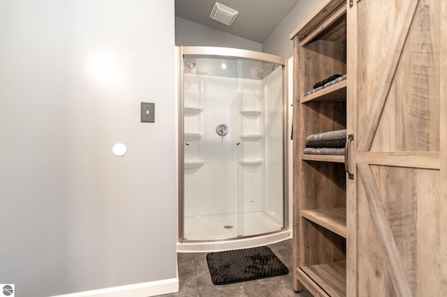 full bathroom with a shower stall and baseboards