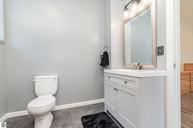 half bathroom with toilet, vanity, and baseboards