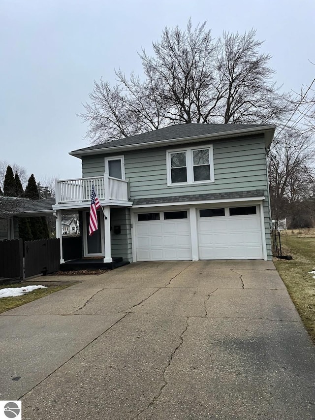 traditional home with an attached garage, concrete driveway, and fence