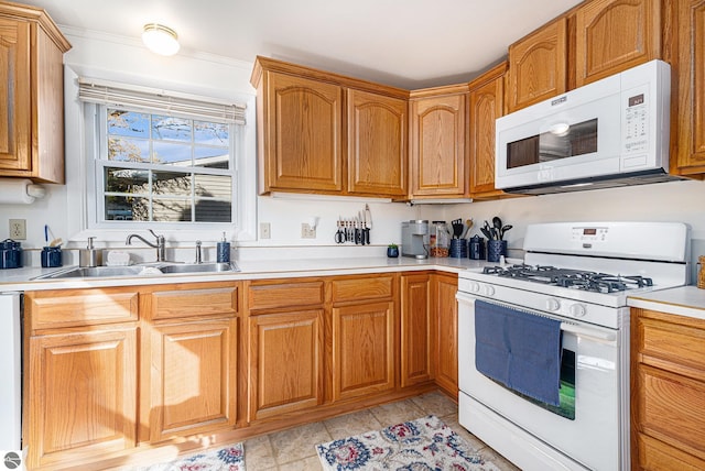 kitchen featuring light countertops, white appliances, a sink, and brown cabinets