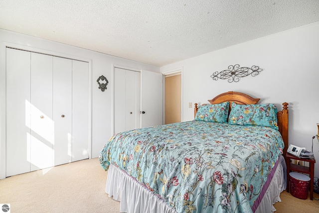 bedroom featuring multiple closets, carpet, and a textured ceiling