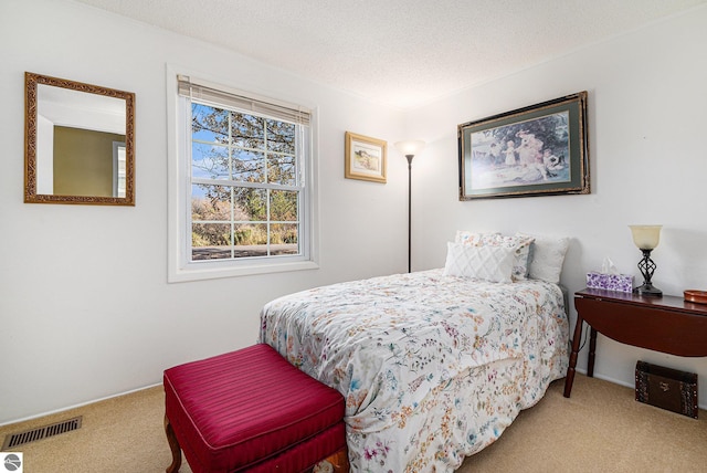 bedroom featuring carpet floors, visible vents, and a textured ceiling