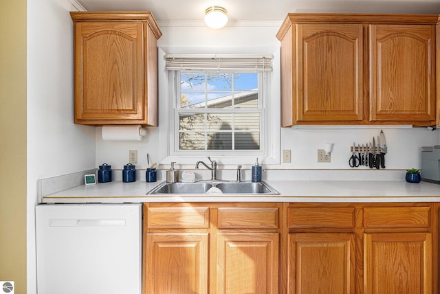 kitchen with brown cabinets, white dishwasher, light countertops, and a sink