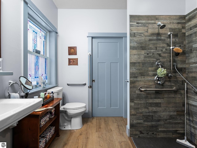 full bath featuring tiled shower, wood finished floors, and toilet