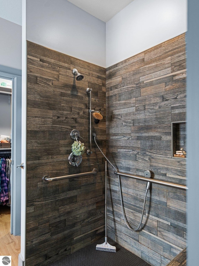 full bathroom with a walk in closet and a tile shower