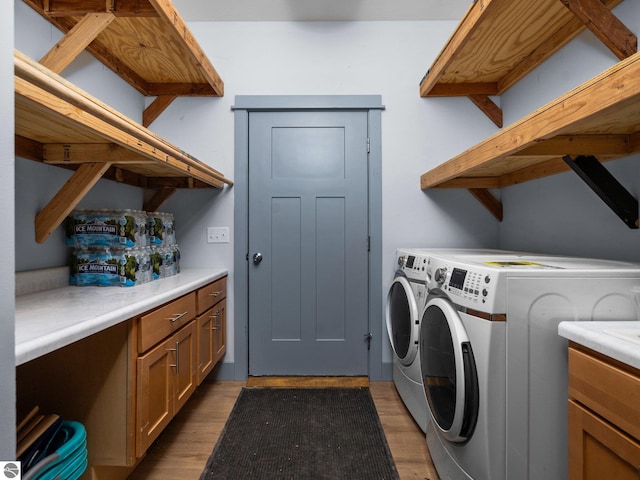 washroom with cabinet space, washing machine and clothes dryer, and wood finished floors