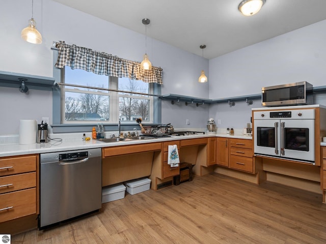 kitchen with stainless steel appliances, light wood-type flooring, a sink, and light countertops