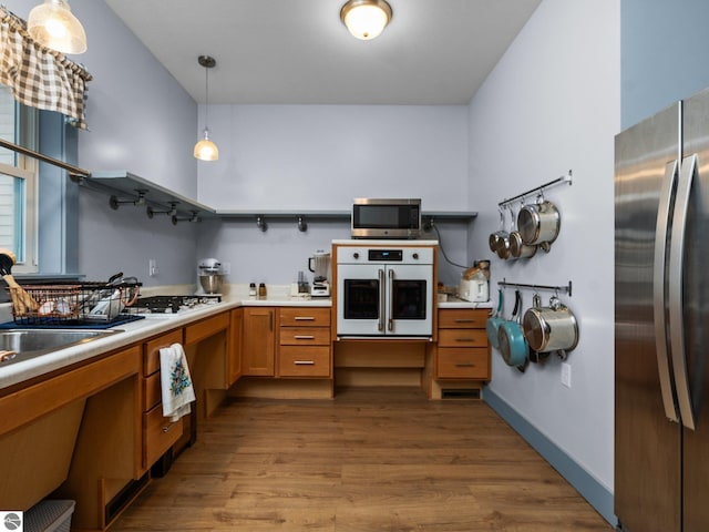 kitchen with wood finished floors, a sink, light countertops, appliances with stainless steel finishes, and open shelves