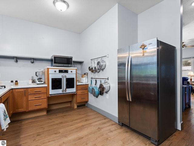 kitchen with stainless steel appliances, light wood-type flooring, light countertops, and brown cabinets