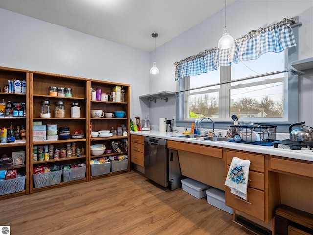 kitchen featuring brown cabinetry, a sink, light countertops, light wood-style floors, and stainless steel dishwasher