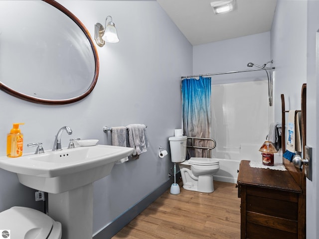 bathroom with shower / bath combo with shower curtain, wood finished floors, toilet, and baseboards