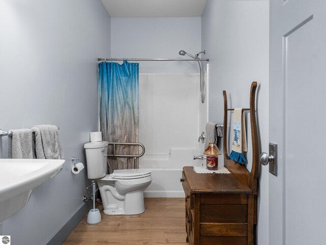 bathroom with shower / bath combo, wood finished floors, toilet, and baseboards