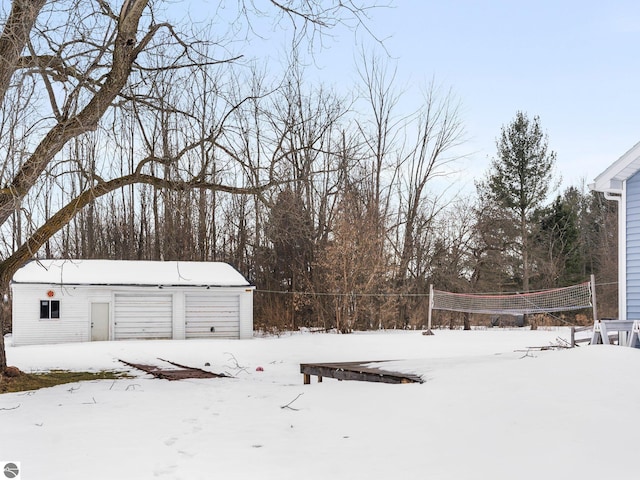 yard layered in snow featuring a detached garage and an outdoor structure