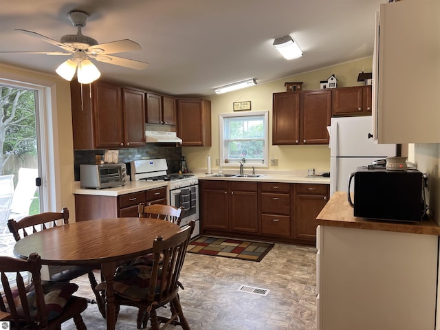 kitchen featuring light countertops, visible vents, a sink, white appliances, and under cabinet range hood