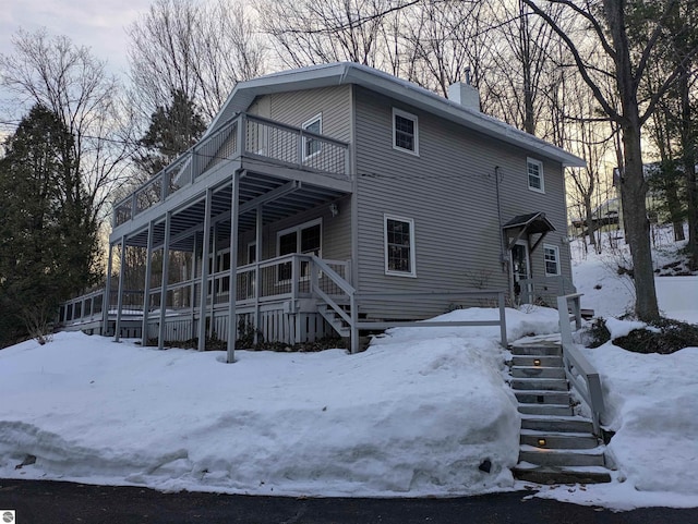 view of front of home with a chimney, stairway, and a wooden deck