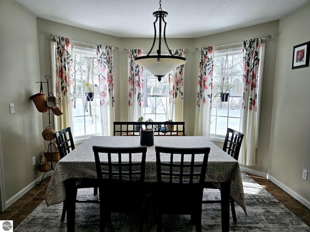 dining space featuring dark tile patterned floors and baseboards