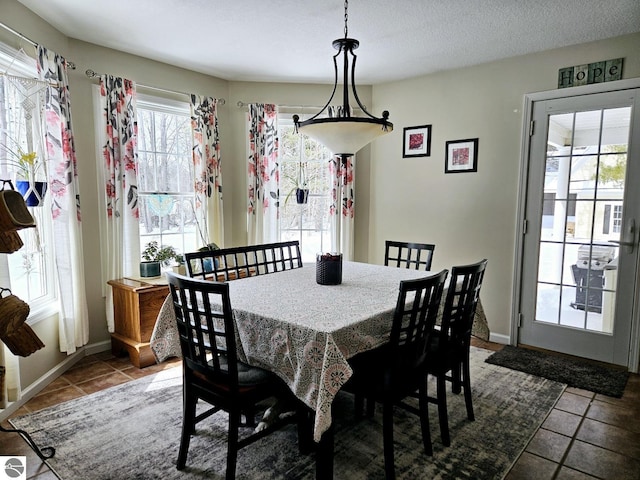 tiled dining room with a textured ceiling and baseboards