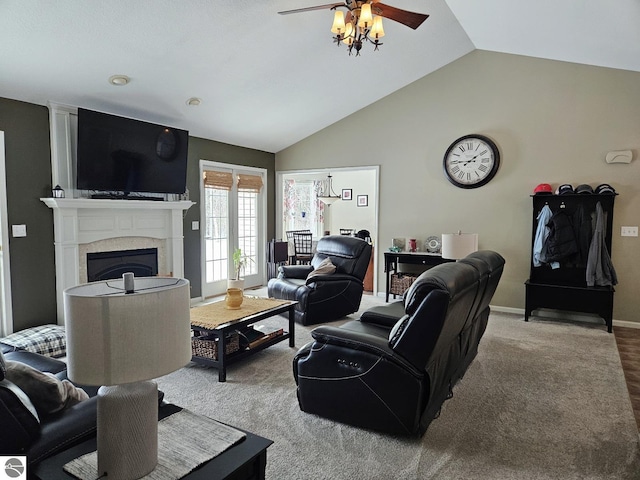 carpeted living room with lofted ceiling, baseboards, a ceiling fan, and a glass covered fireplace