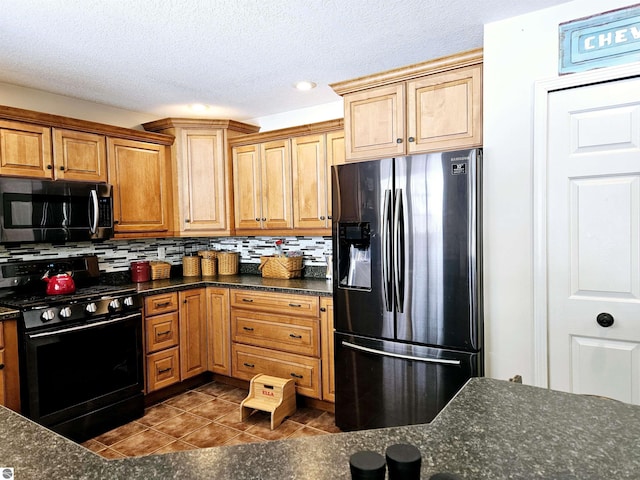 kitchen with backsplash, black range with gas cooktop, fridge with ice dispenser, dark stone countertops, and dark tile patterned flooring