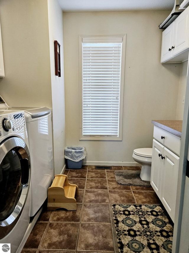 clothes washing area with washing machine and dryer, laundry area, tile patterned flooring, and baseboards