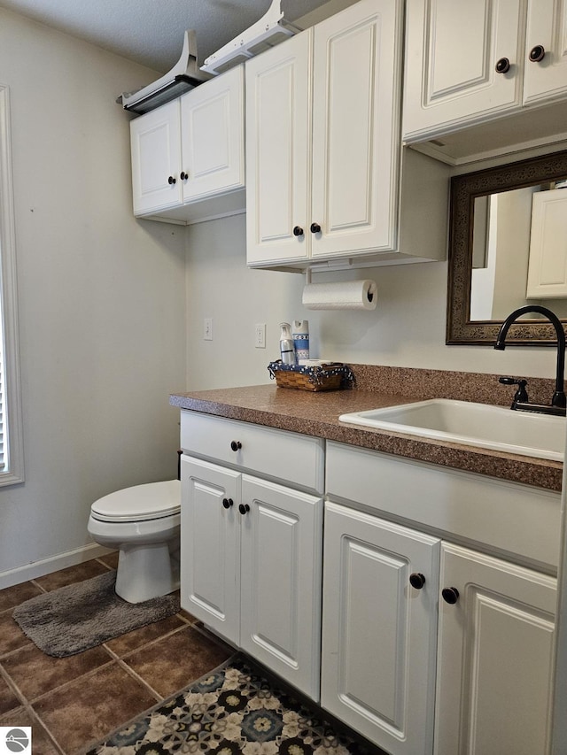 interior space featuring dark countertops, a sink, and white cabinetry