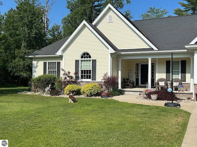 view of front of home featuring covered porch, roof with shingles, and a front yard