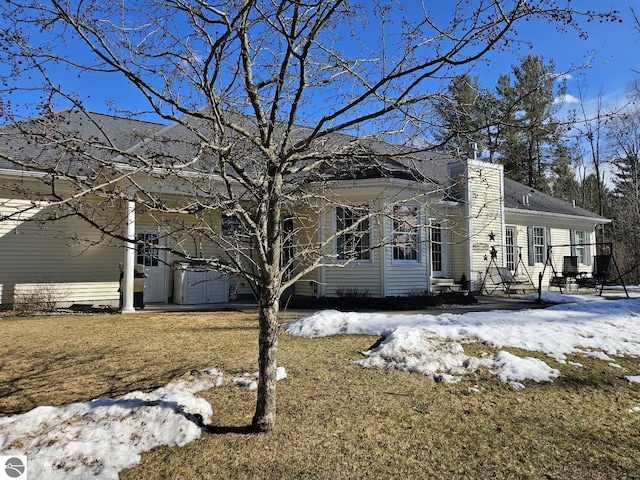 view of snow covered exterior featuring a garage and a chimney