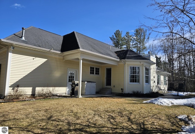 rear view of property with entry steps and a yard