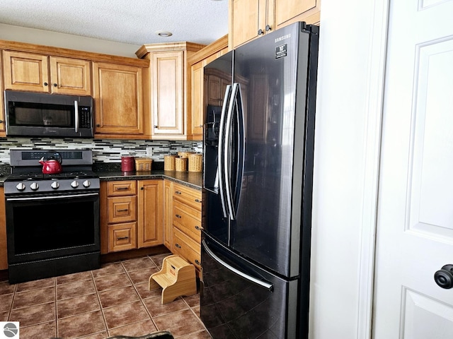 kitchen featuring range with gas cooktop, dark countertops, decorative backsplash, fridge with ice dispenser, and dark tile patterned floors