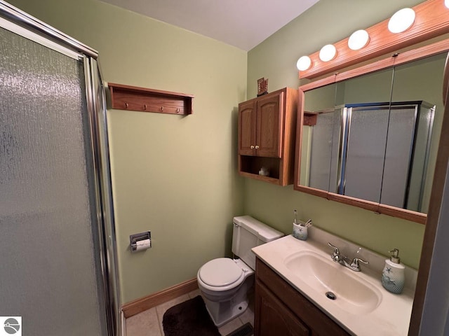 full bathroom featuring tile patterned flooring, toilet, vanity, baseboards, and a shower stall