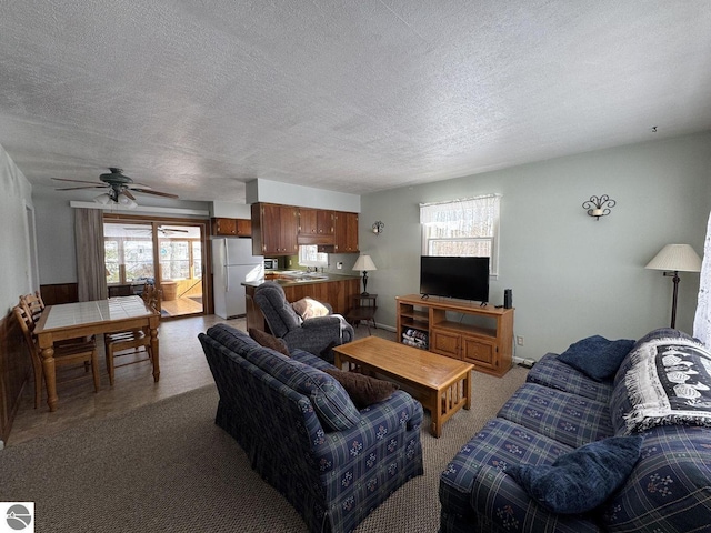 living area featuring a ceiling fan and a textured ceiling