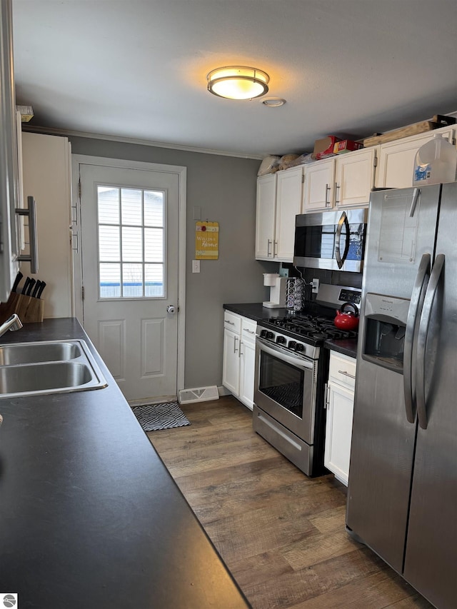 kitchen featuring stainless steel appliances, a sink, dark wood finished floors, and white cabinets