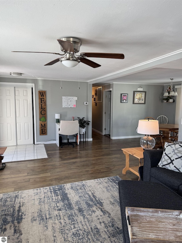 living area with a textured ceiling, ceiling fan, wood finished floors, and baseboards