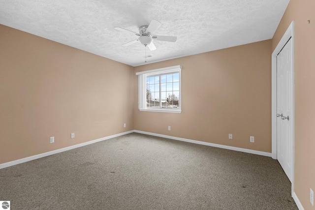 carpeted spare room with a textured ceiling, baseboards, and a ceiling fan