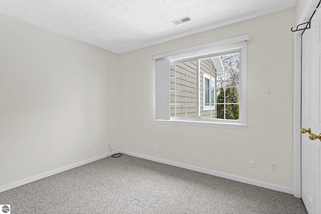 empty room featuring carpet floors, baseboards, visible vents, and a textured ceiling