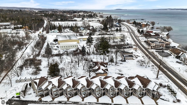 snowy aerial view featuring a water view and a residential view