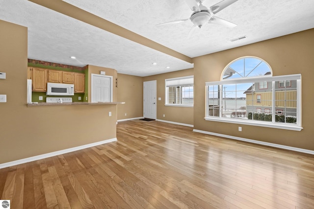 unfurnished living room featuring a wealth of natural light, light wood-style flooring, and baseboards