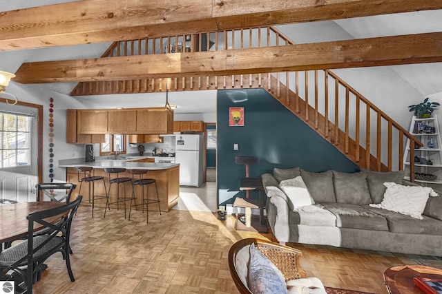 living room with stairs, high vaulted ceiling, and beamed ceiling