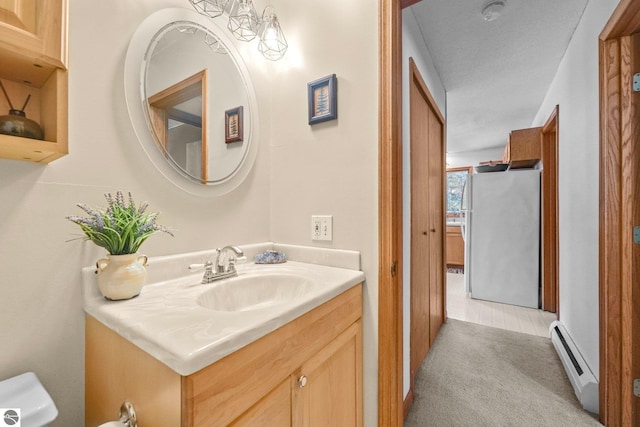 bathroom with a baseboard heating unit, toilet, and vanity