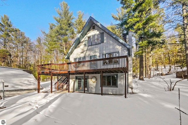 snow covered house with a wooden deck and stairs